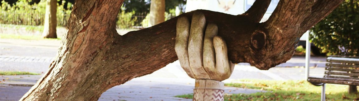 Geschnitzte Holzhand stützt einen schweren Ast – Psychotherapie für Angehörige in Berlin Mitte, Privatpraxis Antje Mühle